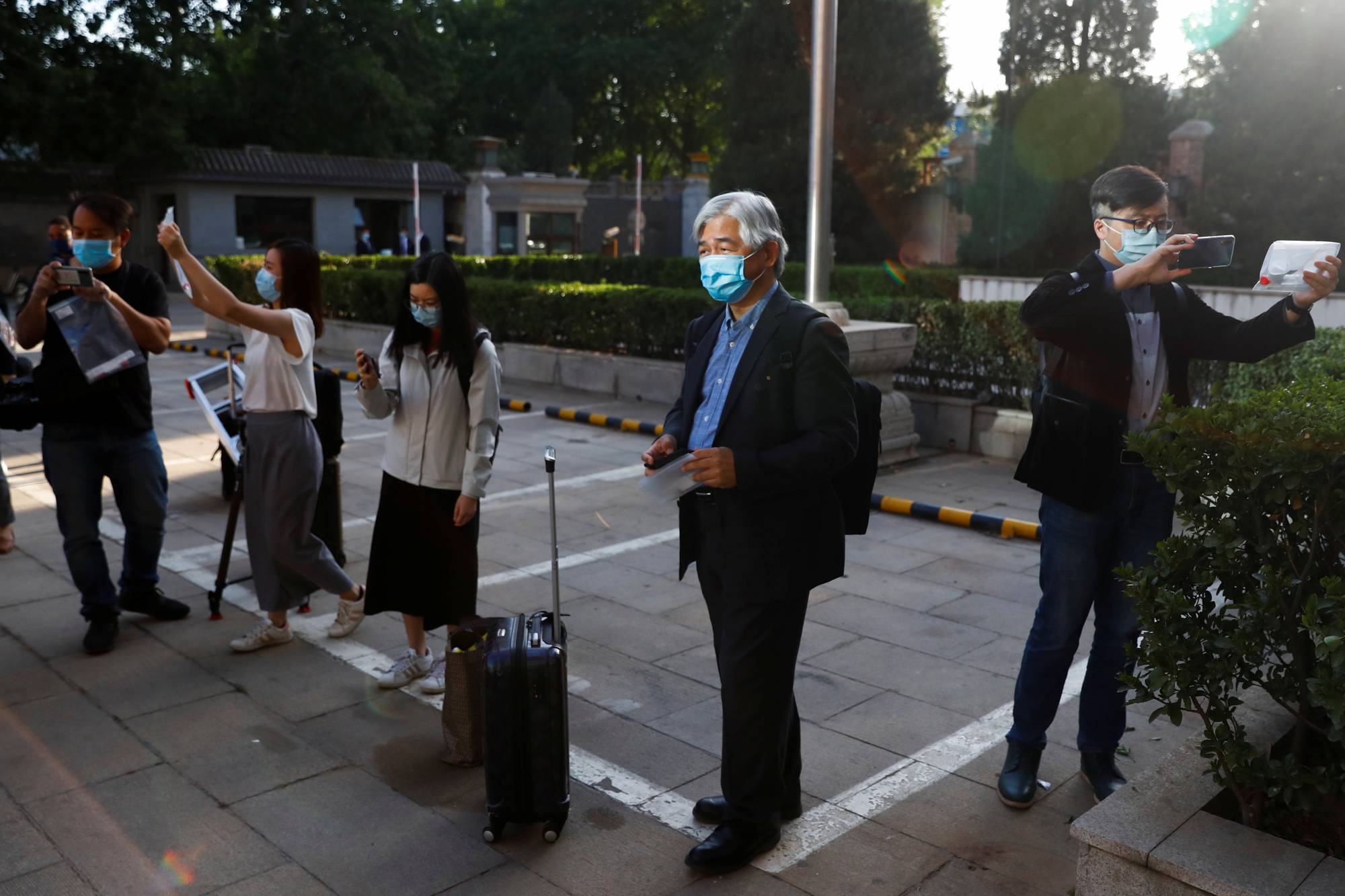 Journalists take pictures and wait to be tested for COVID-19 before attending a news conference in Beijing in May 2020. | REUTERS