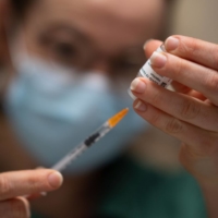 A pharmacist prepares a dose of the AstraZeneca COVID-19 vaccine with a syringe in a pharmacy, in Savenay, western France, on Friday. | AFP-JIJI