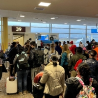 Travelers at Washington Reagan National Airport line up at a departure gate in Arlington, Virginia, in December as the Christmas holiday travel season kicked off. Fully vaccinated people can start traveling again if they take precautions such as wearing a mask and observing social distancing, U.S. health authorities said on Friday. | AFP-JIJI