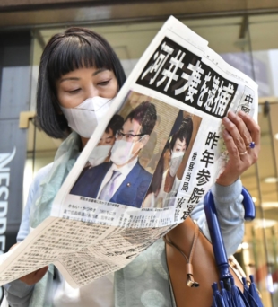A woman receives a copy of a newspaper extra edition in Hiroshima last year after Katsuyuki and Anri Kawai were arrested earlier in the day on suspicion of giving out cash to local politicians in 2019. | KYODO 