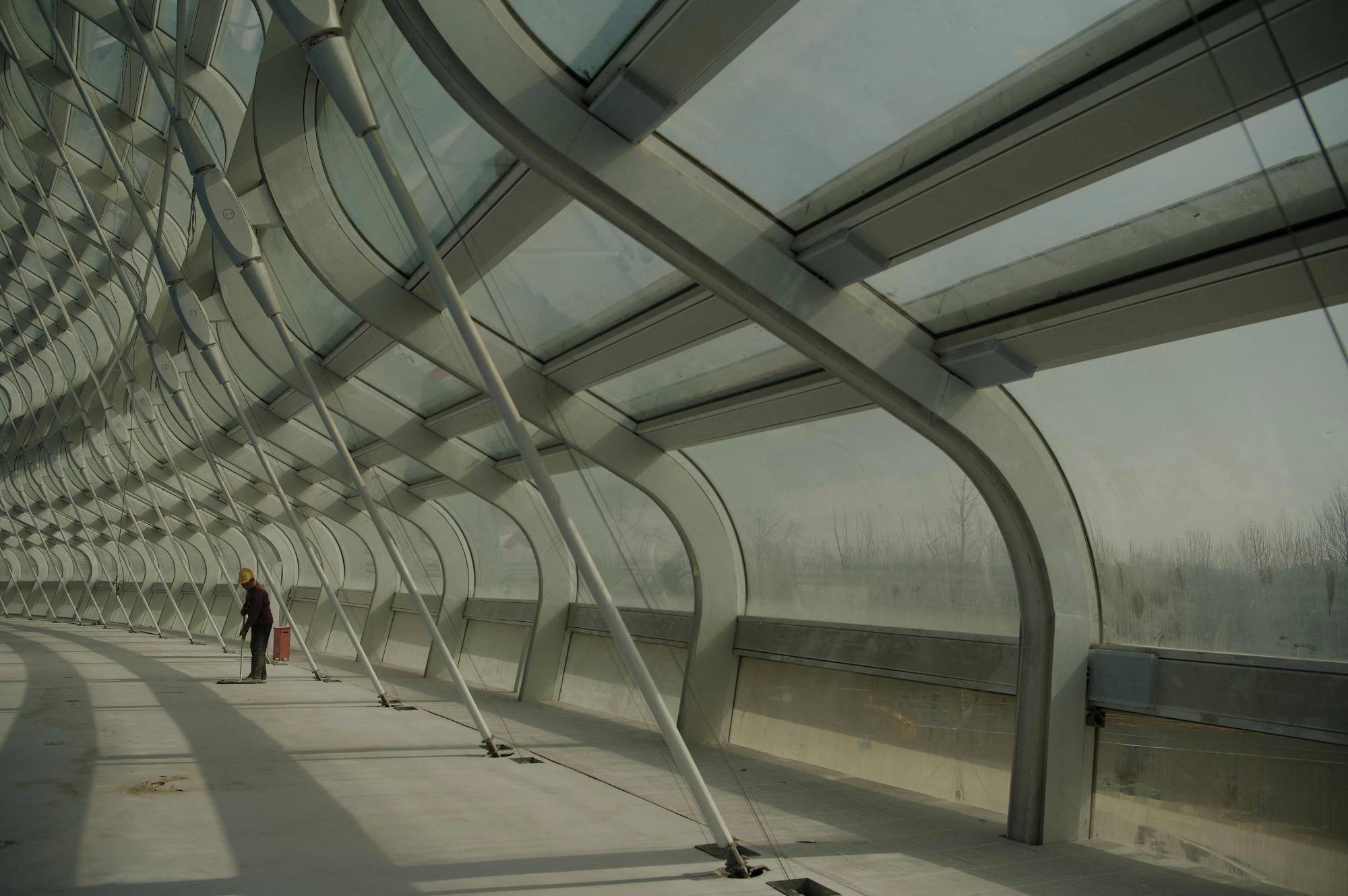 A worker sweeps the floor of the National Speed Skating stadium at Beijing Olympic Park on March 31. | AFP-JIJI