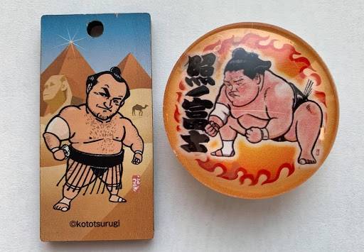 Kototsurugi illustrated countless pieces of merchandise for the Japan Sumo Association, including an Osunaarashi charm (left) and Terunofuji magnet. | John Gunning 