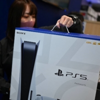 An employee prepares the new Sony PlayStation 5 gaming console for a customer on the first day of its launch at an electronics shop in Kawasaki in November. | AFP-JIJI