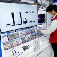 A Bic Camera employee prepares a promotional display for Sony\'s PlayStation 5 game console in Tokyo in November. | REUTERS