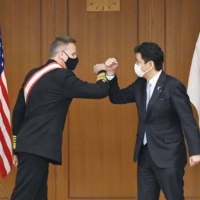 Adm. Philip Davidson (left), the outgoing commander of the U.S. Indo-Pacific Command, and Defense Minister Nobuo Kishi bump arms before their talks in Tokyo on Monday. | KYODO
