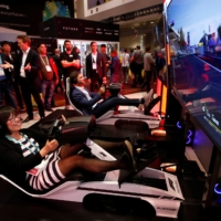 How Hong (left) of Canada tries out a driving simulator in the Formula One Esports League booth during the Consumer Electronics Show in Las Vegas on Jan. 7, 2020. | REUTERS