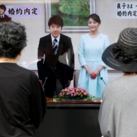 People watch news coverage of the engagement of Princess Mako and Kei Komuro in Tokyo in 2017. A survey last month saw 97% of respondents opposed to the marriage. | REUTERS