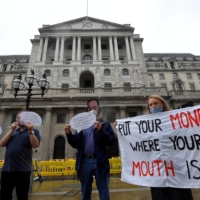 Environmental activists wear masks depicting Bank of England Gov. Andrew Bailey during a protest to encourage a green economy, outside of the Bank of England in the City of London in 2020. | REUTERS 