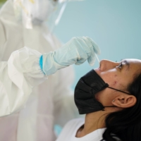 A health care worker takes a nasal swab sample from a person for a coronavirus test in Bangkok on Friday.  | REUTERS