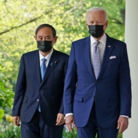 U.S. President Joe Biden and Prime Minister Yoshihide Suga walk to take part in a joint news conference in the Rose Garden of the White House in Washington on Friday. | AFP-JIJI