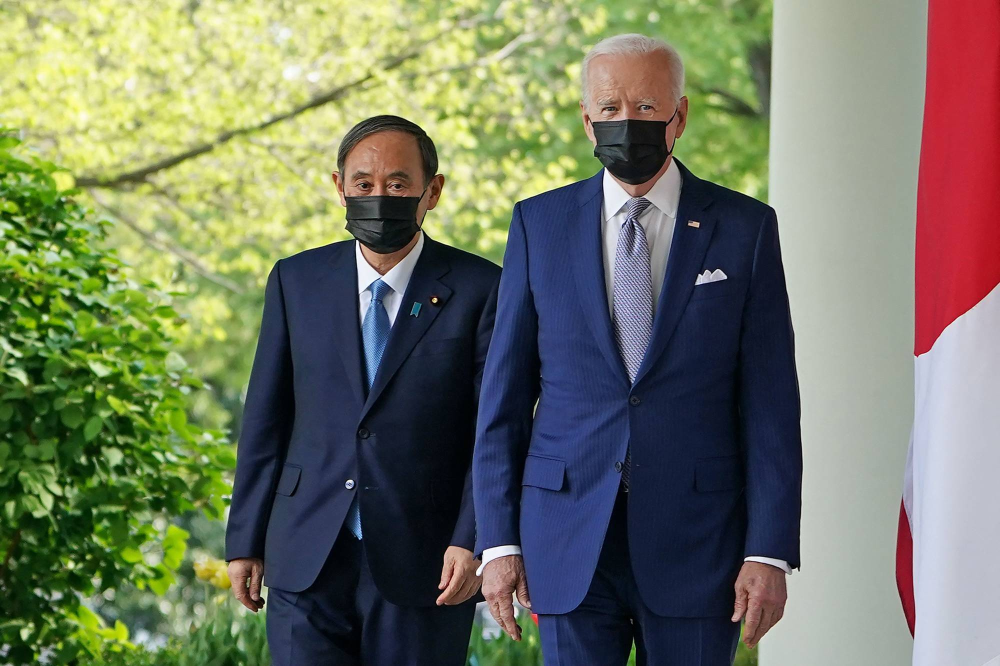 U.S. President Joe Biden and Prime Minister Yoshihide Suga walk to take part in a joint news conference in the Rose Garden of the White House in Washington on Friday. | AFP-JIJI