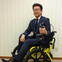 Kenji Suzuki, founder and representative director of TESS Co., showcases one of the startup\'s revolutionary pedal-powered wheelchairs.  | COURTESY OF TESS
