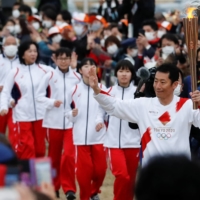 Japanese aerobatics pilot Yoshihide Muroya carries the Olympic torch at Hibarigahara Festival Site in Minamisoma, Fukushima Prefecture, during the last leg of the first day of the Tokyo 2020 Olympic torch relay last month. | REUTERS