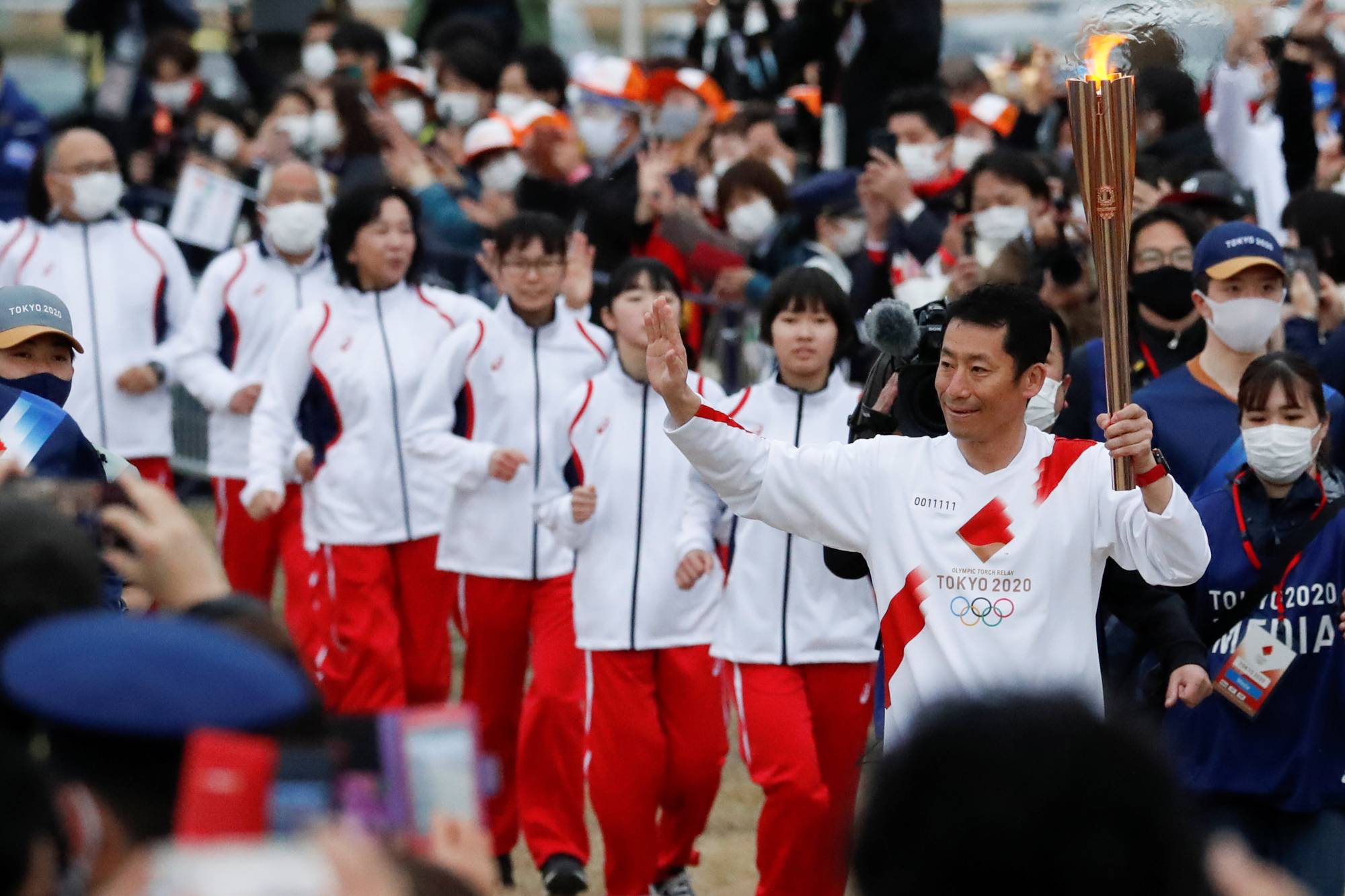 Japanese aerobatics pilot Yoshihide Muroya carries the Olympic torch at Hibarigahara Festival Site in Minamisoma, Fukushima Prefecture, during the last leg of the first day of the Tokyo 2020 Olympic torch relay last month. | REUTERS