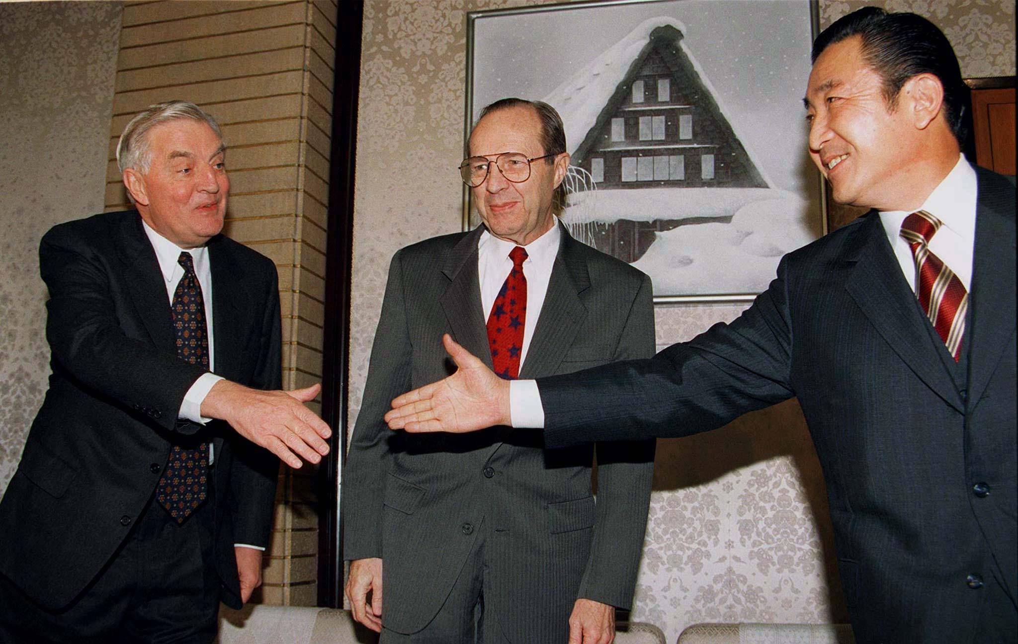 Prime Minister Ryutaro Hashimoto (right) extends his hand to Ambassador to Japan Walter Mondale (left) at the Prime Minister's Office in Tokyo as U.S. Defense Secretary William Perry looks on in December 1996. | REUTERS