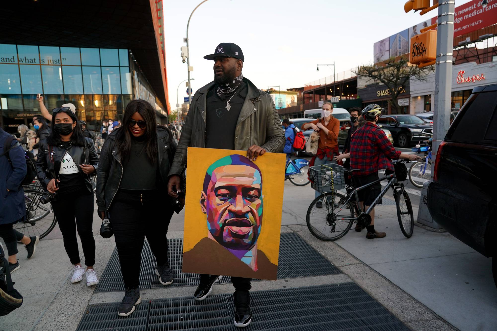 A man carries a portrait of George Floyd as people gather outside the Barclays Center in Brooklyn, New York, on Tuesday. | Michelle V. Agins / The New York Times