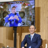Japanese astronaut Soichi Noguchi and Prime Minister Yoshihide Suga laugh during a call from the International Space Station on Tuesday evening at the Prime Minister\'s Office in Tokyo. | KYODO