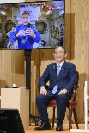 Japanese astronaut Soichi Noguchi and Prime Minister Yoshihide Suga laugh during a call from the International Space Station on Tuesday evening at the Prime Minister's Office in Tokyo. | KYODO