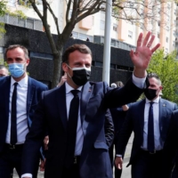 French President Emmanuel Macron waves to residents of La Mosson suburban neighborhood during his visit in Montpellier, southern France, on Monday. | POOL / VIA REUTERS