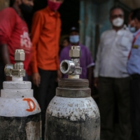 Workers load refilled oxygen tanks into a vehicle in Navi Mumbai, India, on Thursday. | BLOOMBERG 