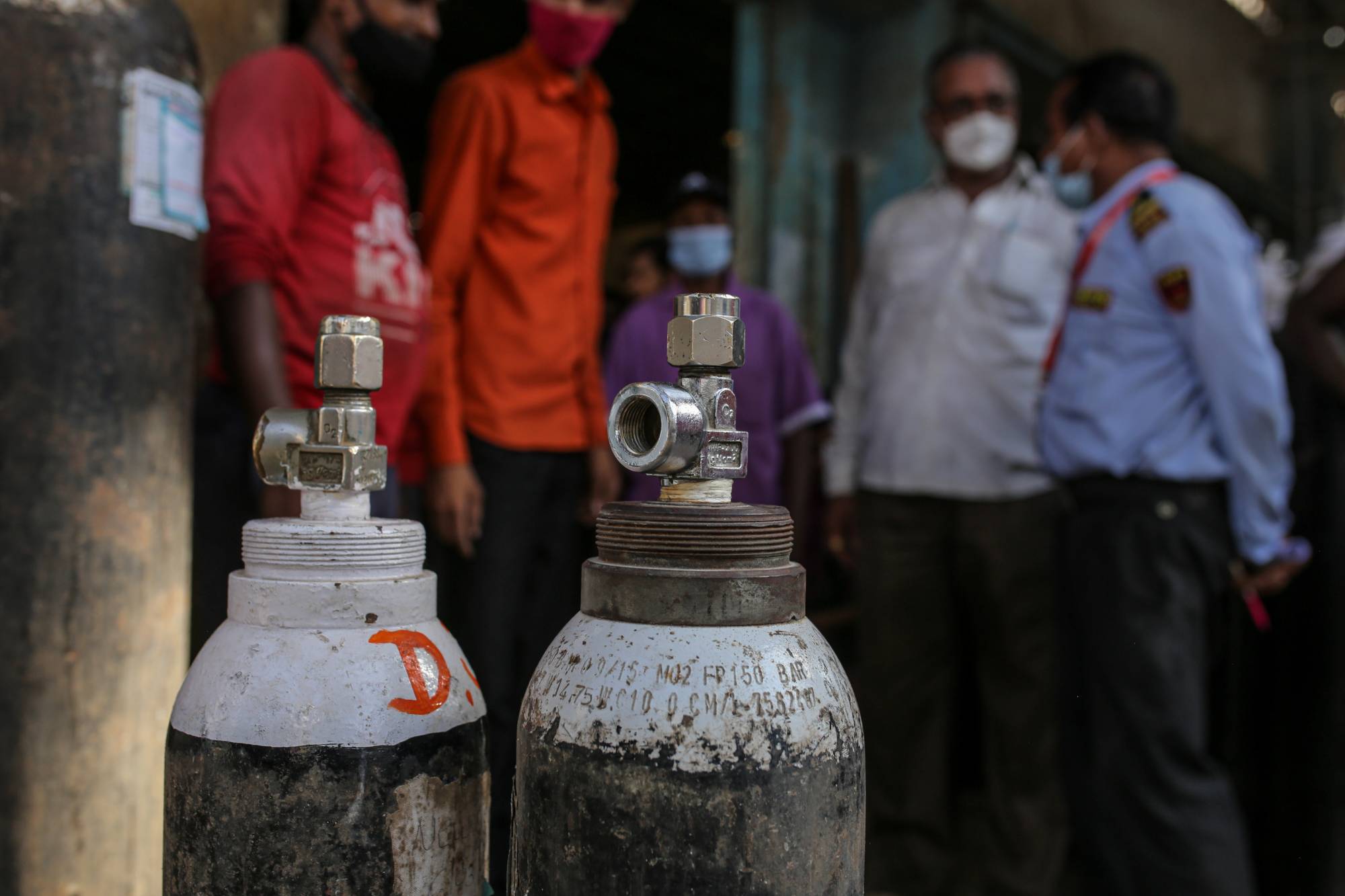 Workers load refilled oxygen tanks into a vehicle in Navi Mumbai, India, on Thursday. | Bloomberg 
