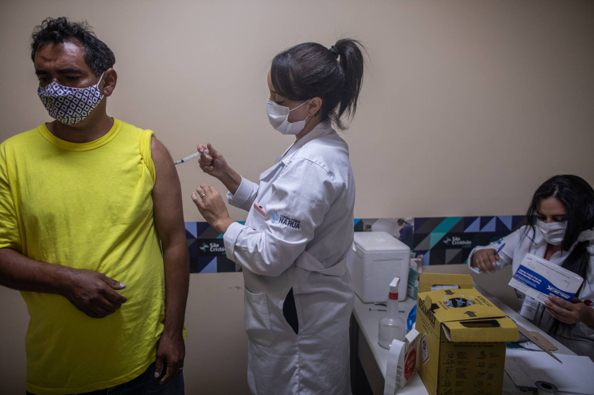 In process: A health care worker administers a dose of the Sinovac Biotech CoronaVac COVID-19 vaccine to a person at a community shelter in Sao Paulo, Brazil, on April 22. The Brazilian government is adding 1.6 billion reals ($286 million) in funding to purchase vaccines, medicines and expand intensive care centers around the country. | BLOOMBERG