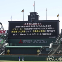 Details regarding NPB\'s response to the new state of emergency in Japan are displayed on a video board at Koshien Stadium in Nishinomiya, Hyogo Prefecture, on Sunday. | KYODO