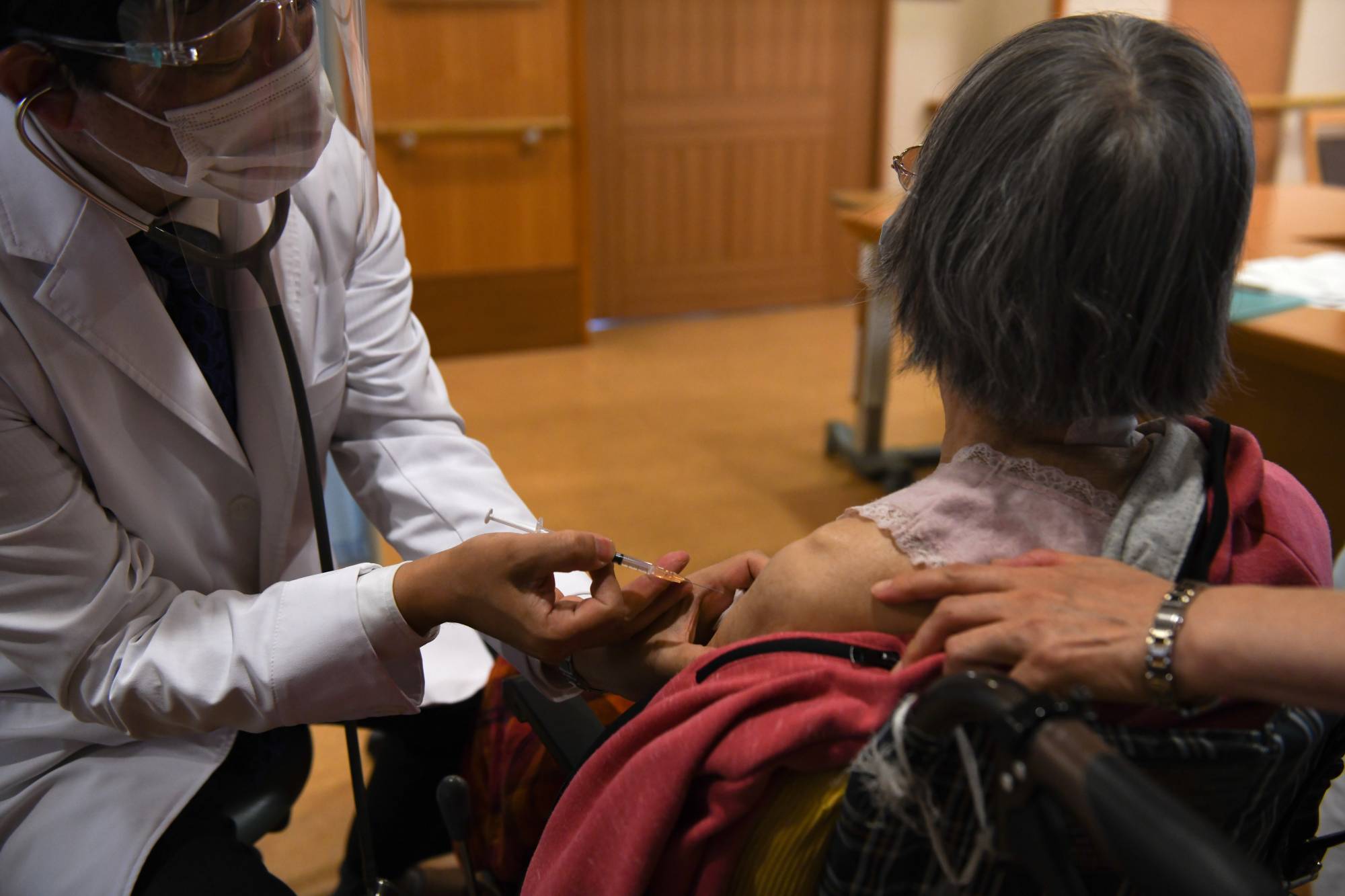 A doctor administers a dose of a COVID-19 vaccine at a nursing home in Kawasaki on April 12. | BLOOMBERG