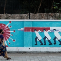 A woman walks past graffiti on a street in Mumbai on March 30. | REUTERS