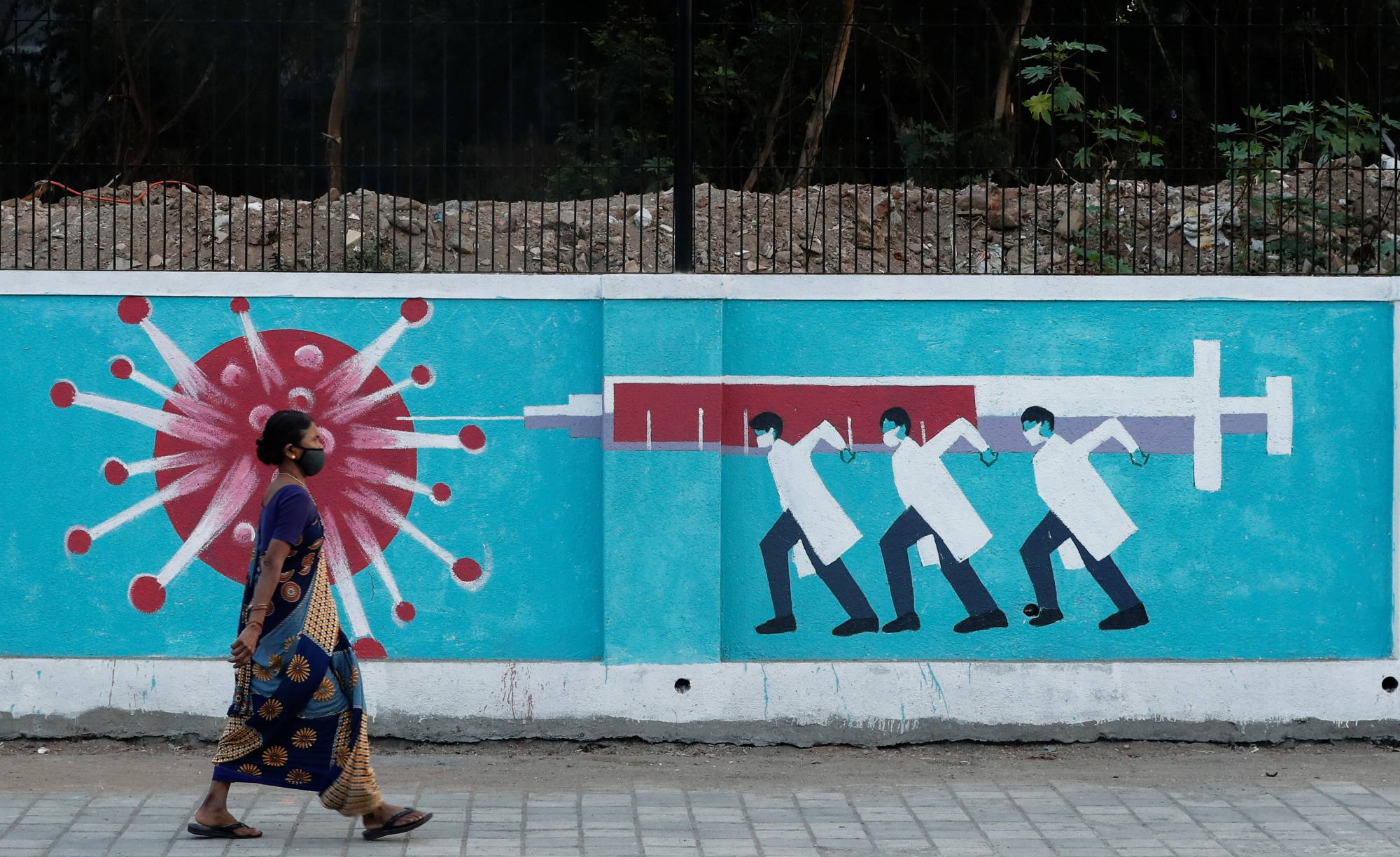 A woman walks past graffiti on a street in Mumbai on March 30. | REUTERS