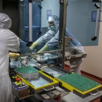 Employees work on the production of line for Covishield, the local name for the COVID-19 vaccine developed by AstraZeneca PLC and the University of Oxford, at the Serum Institute of India Ltd. Hadaspar plant in Pune, Maharashtra, India, in January.  | BLOOMBERG 