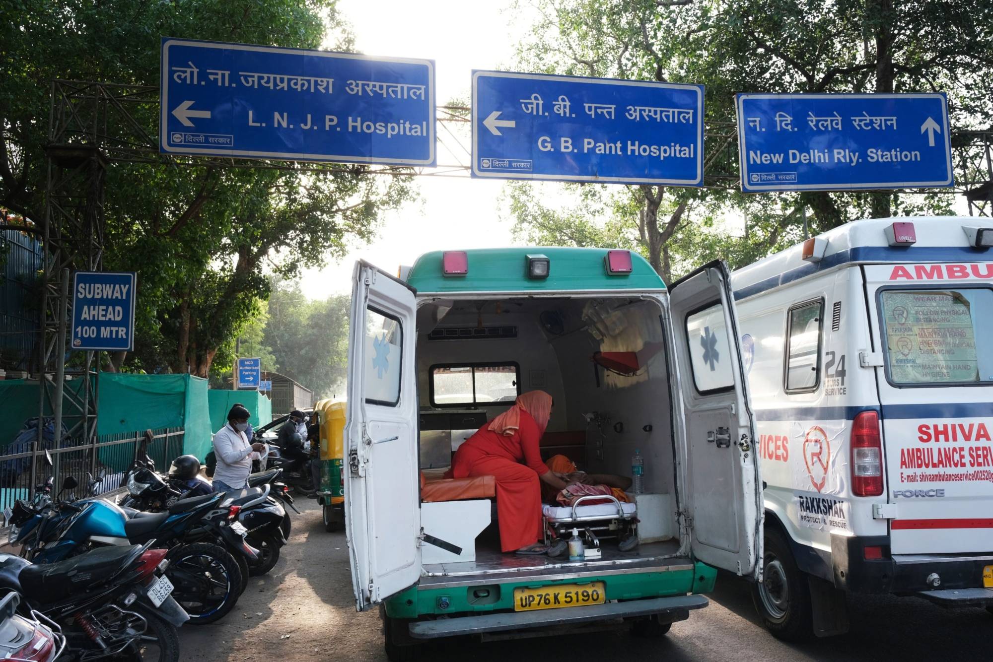 A COVID-19 patient is attended to in ambulance while waiting at the main entrance of the Lok Nayayak Jaiprakash Hospital in New Delhi on Saturday. | Bloomberg 