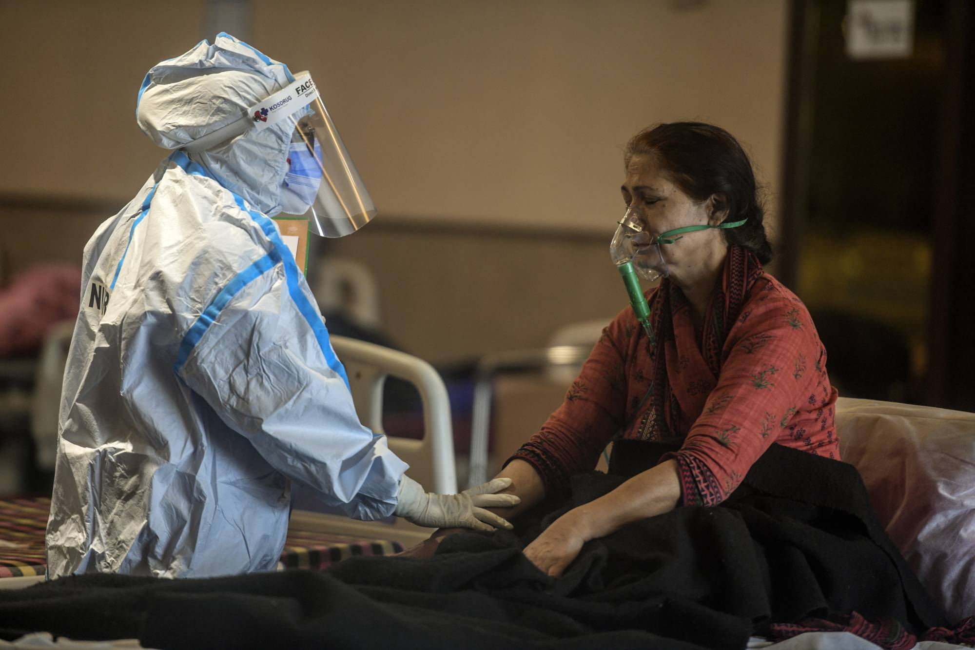 A health care worker speaks to a COVID-19 patient at a temporary treatment site set up near a hospital in Delhi on Friday. | Atul Loke / The New York Times