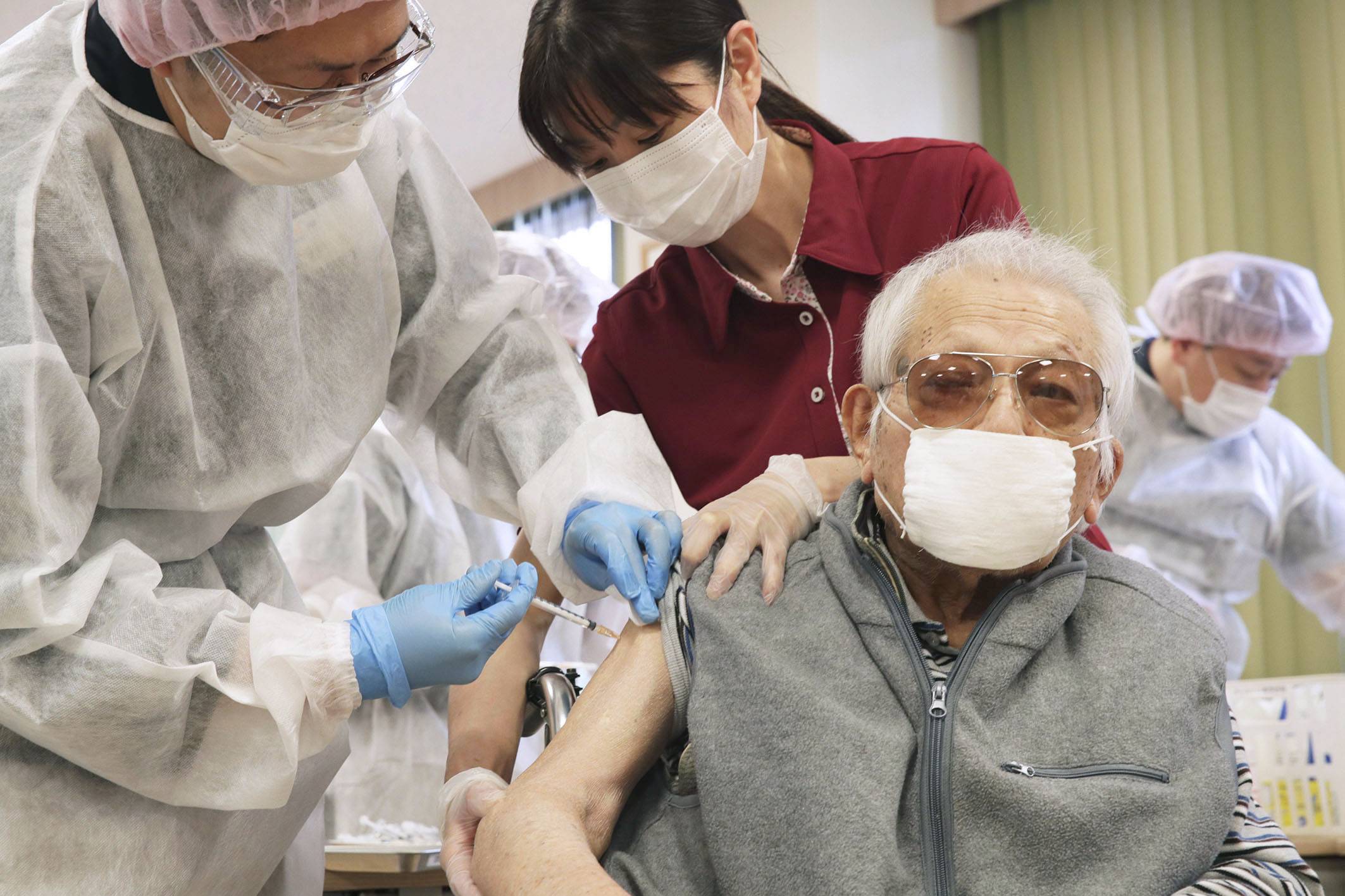 A man receives a COVID-19 vaccine shot at a nursing care facility in Tokyo's Setagaya Ward on April 12. | POOL / VIA KYODO
