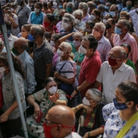 People wait to enter a COVID-19 vaccination center in Mumbai on Tuesday.  | BLOOMBERG 