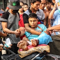 A wounded person is carried to hospital as people continue to protest against the military coup in Yangon, Myanmar, on March 14. | GETTY IMAGES / VIA KYODO