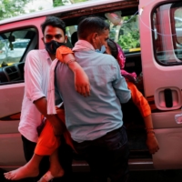 A man carries a woman suffering from breathing problems in Ghaziabad, India, on Friday. | REUTERS