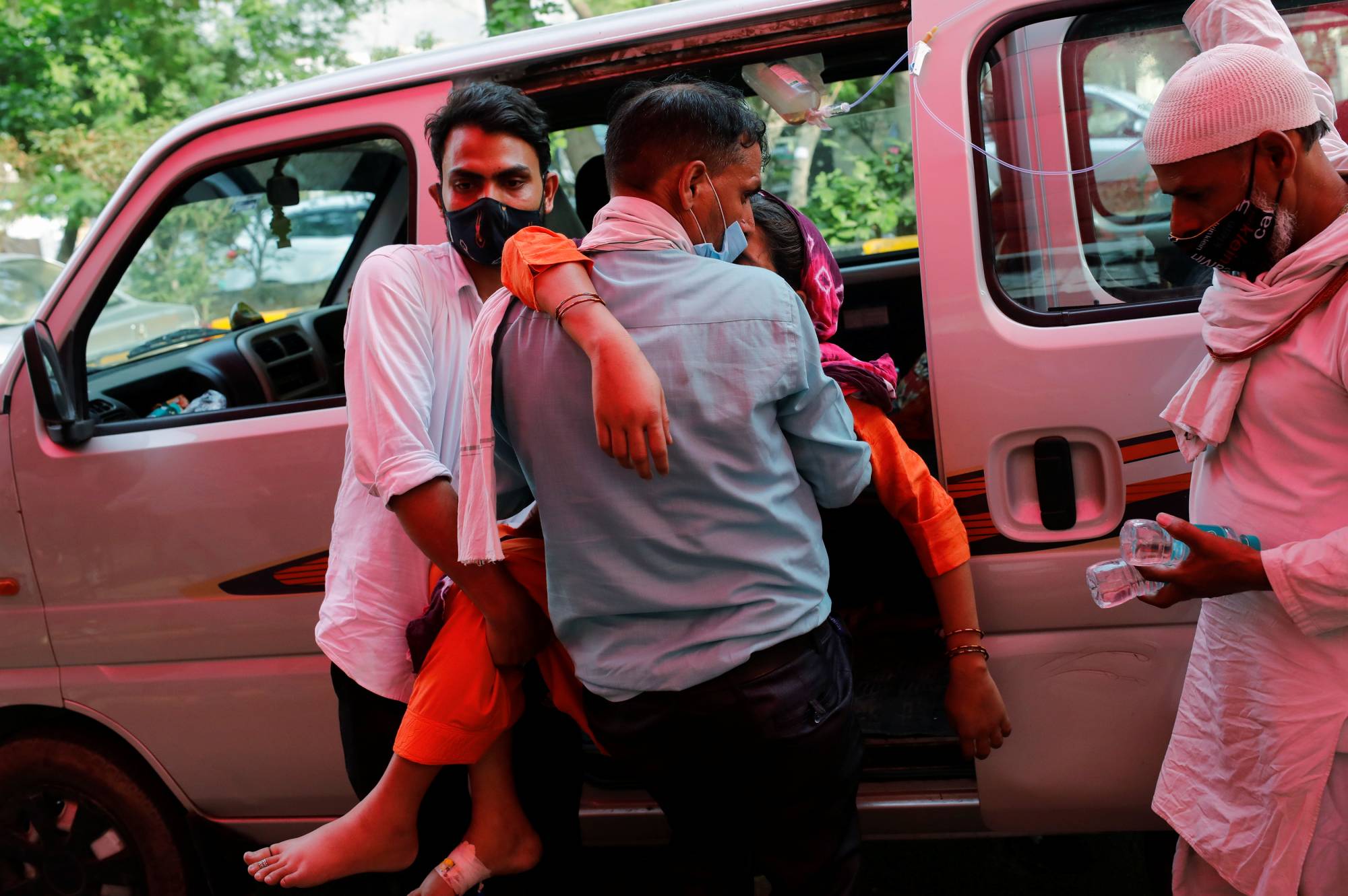 A man carries a woman suffering from breathing problems in Ghaziabad, India, on Friday. | REUTERS
