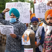 Demonstrators hold oxygen cylinders as they shout slogans protesting Indian lawmakers during a rally in Amritsar on Friday. | AFP-JIJI
