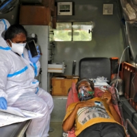 A paramedic checks medical reports of a patient inside an ambulance before heading to a hospital caring for coronavirus patients as COVID-19 spreads in Ahmedabad, India, on Thursday.  | REUTERS