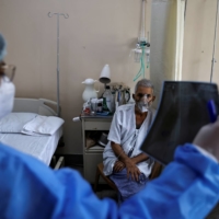 A doctor checks an X-ray of a patient suffering from COVID-19 at a hospital in New Delhi on Saturday.  | REUTERS