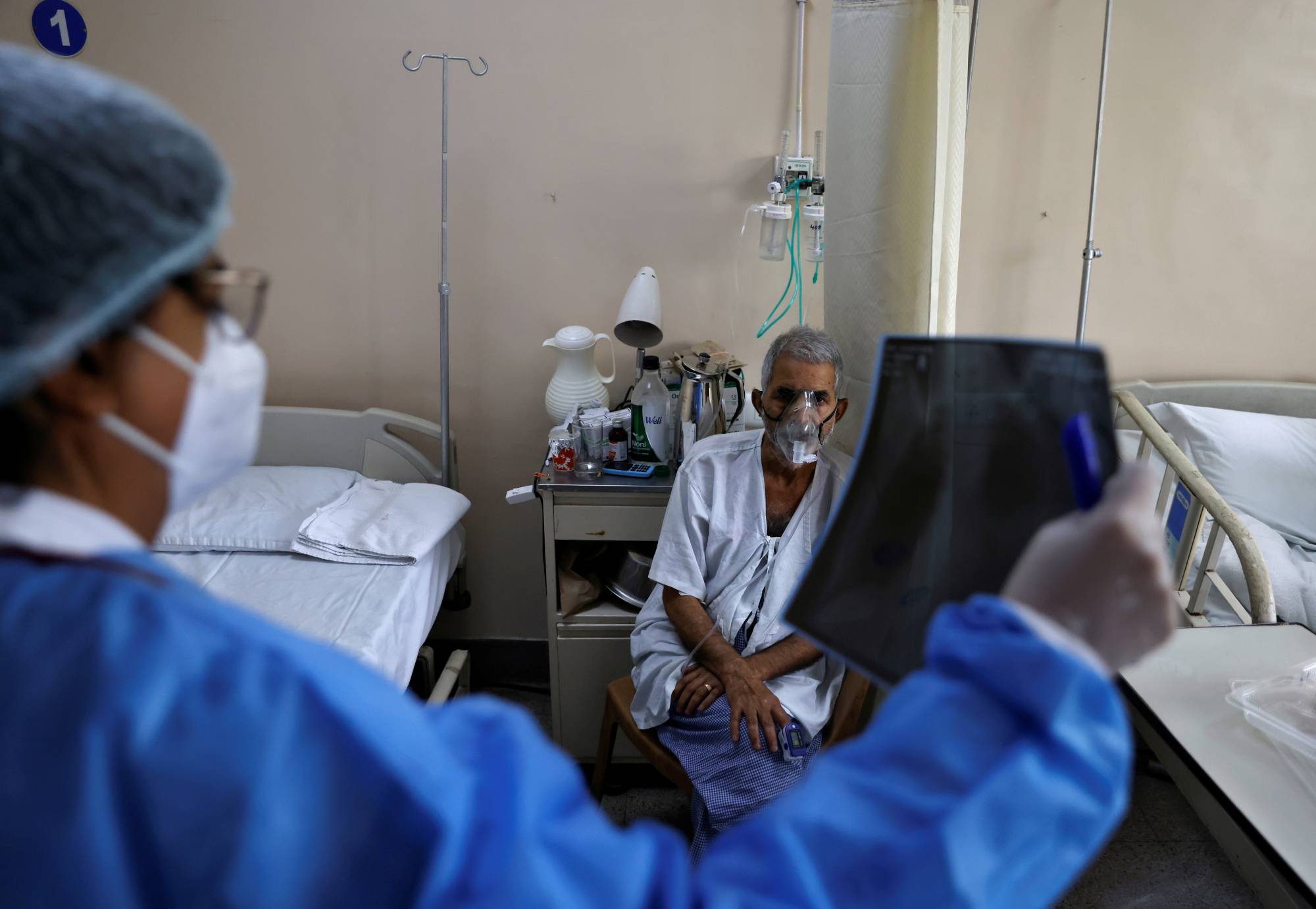 A doctor checks an X-ray of a patient suffering from COVID-19 at a hospital in New Delhi on Saturday. | Reuters