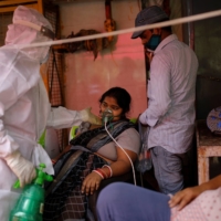 A woman with a breathing problem receives oxygen support  at a temple in Ghaziabad, India, on Friday.  | REUTERS 