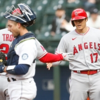 Angels designated hitter Shohei Ohtani (right) celebrates with teammate Mike Trout after scoring on Trout\'s home run against the Mariners on Saturday in Seattle. | USA TODAY / VIA REUTERS