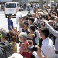 People watch the Olympic torch relay on Amami Oshima island in Kagoshima Prefecture on Tuesday. | KYODO