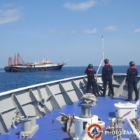 Philippine Coast Guard personnel survey several ships believed to be Chinese militia vessels in the South China Sea on April 27.  | PHILIPPINE COAST GUARD / VIA REUTERS