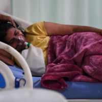 A COVID-19 patient breaths with the help of an oxygen mask inside the intensive care unit of the Teerthanker Mahaveer University hospital in Moradabad, India on Wednesday. | AFP-JIJI
