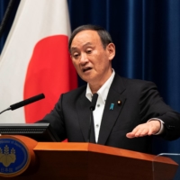 Prime Minister Yoshihide Suga responds to a reporter’s question during a news conference in Tokyo on Friday night. | POOL / VIA REUTERS