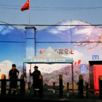 Security guards stand at the gates of what is officially known as a vocational skills education center in China\'s Xinjiang region in September 2018. | REUTERS