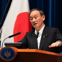 Prime Minister Yoshihide Suga speaks at a news conference in Tokyo on Friday after the government announced an extension of a coronavirus state of emergency. | POOL / VIA AFP-JIJI